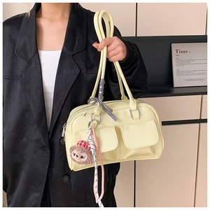 Detail view of a vintage beige Boston bag with dual pockets and plush charm accessory