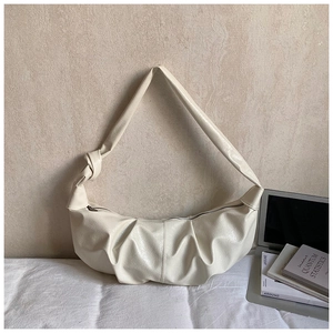 Detail of cream pleated moon bag featuring knotted strap and textured vegan leather