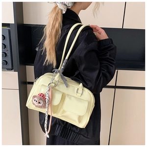 Detail of yellow shoulder bag featuring dual front pockets and checkered bow charm accessory