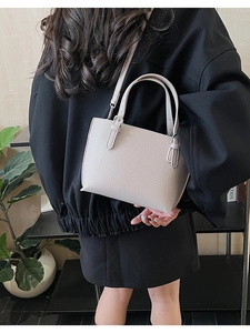 Litchi pattern leather handbag shown on model with adjustable shoulder strap and silver hardware