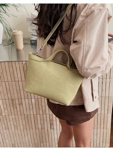 Detail of light green leather tote bag featuring silver hardware and detachable shoulder strap
