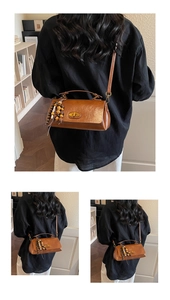 Détail d'un sac bandoulière vintage marron avec fermoir tournant en métal et perles en bois