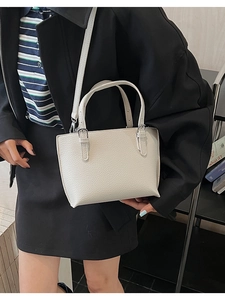 Close-up of minimalist off-white lychee grain leather tote bag with silver buckle details