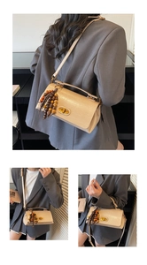 Détail du sac à main en cuir crème avec pompon en bois et fermoir rotatif doré