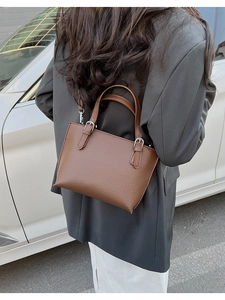Deep brown litchi pattern leather tote bag shown in a stylish street style crossbody pose
