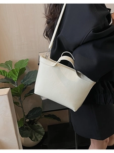 Detail of minimalist cream faux leather handbag with shoulder strap and silver hardware