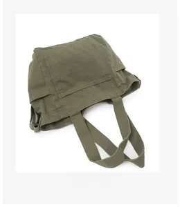 Flat lay macro of army green canvas tote showing durable fabric texture and side pockets