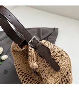 Détail de la bandoulière en cuir réglable et boucle argentée sur un sac en paille