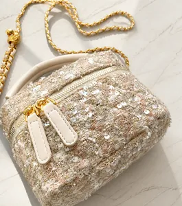 Detailed close-up of sequin tweed fabric texture and gold chain on the square bag