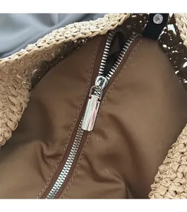 Gros plan sur la fermeture éclair en métal et la doublure en tissu brun du sac en paille