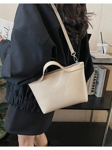 Detail of a minimalist beige PU leather trapezoid handbag with a slim shoulder strap