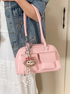 Pink Boston handbag with front pockets and plush charm worn by model in casual outfit