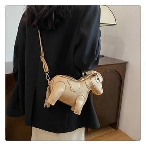 Detail of creative gold pony crossbody bag with metallic finish and tassel charm