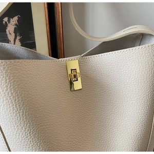 Nahaufnahme des goldenen Drehverschlusses an der beigen Leder-Beuteltasche mit Narbung