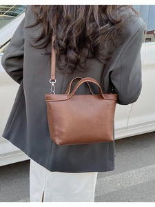 Detailed view of the brown leather texture and stitching on the minimalist shoulder bag