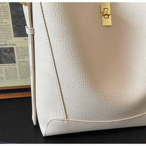 Detail der cremeweißen Schultertasche aus genarbtem Leder mit goldenem Drehverschluss