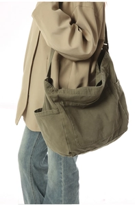 Detailed close-up of army green canvas crossbody bag showing large front pocket and stitching