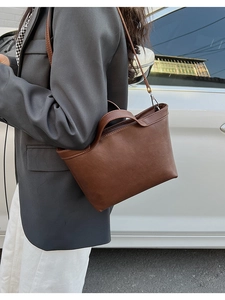 Close-up of a dark brown matte leather handbag with precise stitching and round handles