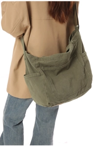 Detail view of large army green canvas crossbody bag showing spacious pockets and straps