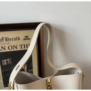 Detail der cremeweißen Beuteltasche aus Leder mit Lychee-Narbung und Goldbeschlägen