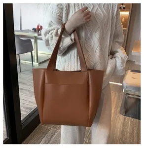 Detail van de karamel lederen tote bag met voorvak gedragen door model in gebreide trui