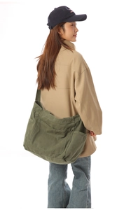 Detail view of large army green canvas crossbody bag showing texture and spacious side pockets