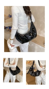 Macro detail of glossy black pleated hobo bag with smooth reflective leather texture