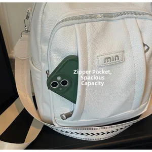 Détail de la poche zippée avant du sac à dos blanc en cuir grainé avec logo métal