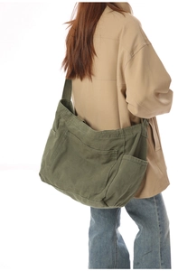 Detail of army green canvas crossbody bag with multiple functional exterior pockets