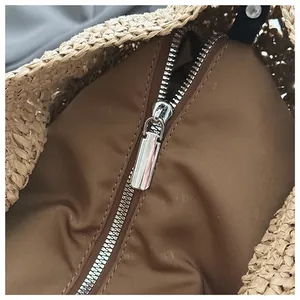 Gros plan du sac en paille tressée avec doublure en tissu marron et fermeture éclair argentée