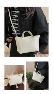Detail of off-white faux leather tote bag with smooth top handle and pebbled texture
