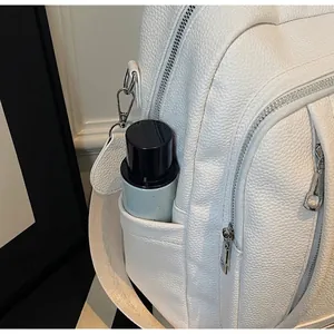 Vue détaillée de la poche latérale d'un sac à dos blanc en cuir avec une bouteille