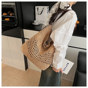 Gros plan détaillé d'un grand sac cabas en paille tressée avec motifs ajourés et anses