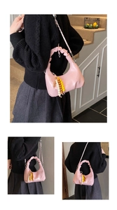 Detail of pink hobo bag with pleated handle, glossy finish, and beaded tassel charm