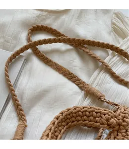 Détail de la bandoulière tressée avec fermoir doré sur un sac de plage en paille