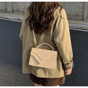 Vue extérieure d'un sac bandoulière beige avec texture crocodile et coutures en forme de V