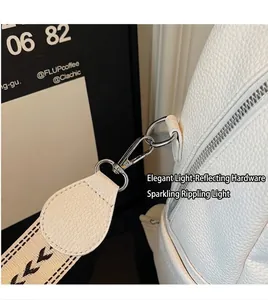 Détail du sac en cuir litchi blanc avec boucle en métal argenté et bandoulière tissée chic