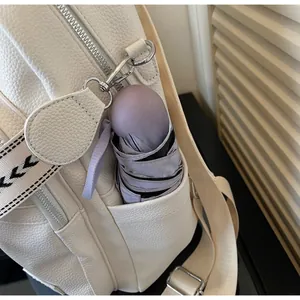 Macro side view of beige leather backpack side pocket holding a small purple umbrella