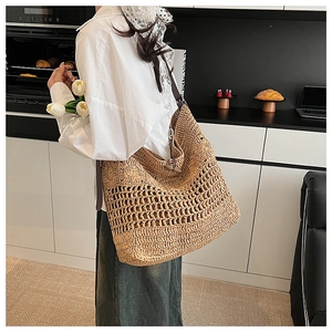 Détail du sac cabas en paille tissée avec texture ajourée et bandoulière en cuir de qualité