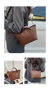 Detail of caramel brown leather tote bag with round handles and adjustable silver strap