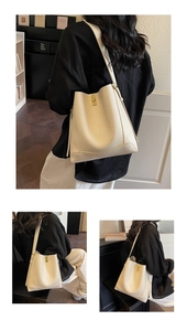 Detail der cremeweißen Eimer-Tasche aus Lychee-Leder mit goldener quadratischer Schnalle