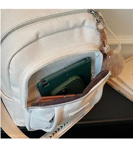 Détail de la poche avant du sac à dos blanc contenant des tablettes et un portefeuille