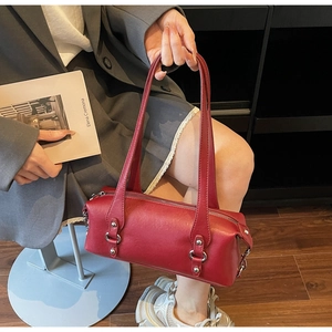 Detail of red leather cylinder handbag with silver zippers and elegant long top handles