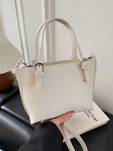 Minimalist creamy white lychee leather bucket bag with top handle and adjustable strap