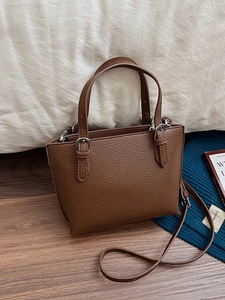 Minimalist dark brown leather bucket bag with top handles and adjustable shoulder strap