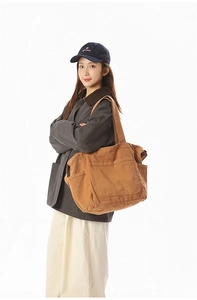 Brown canvas tote bag with multi-pocket design shown on model for casual wear