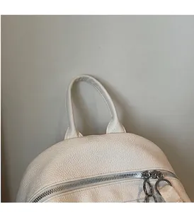 Détail d'un sac à dos blanc en cuir grainé avec doubles fermetures éclair argentées et poignée