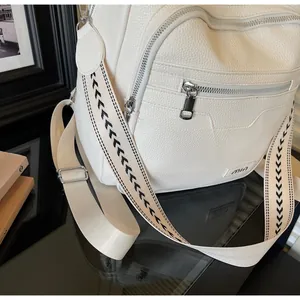 Close-up of white lychee texture backpack with metallic zippers and wide geometric strap