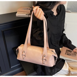 Detail view of pink leather barrel bag with long double straps and metal buckles worn by model