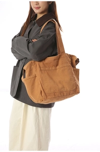 Detail view of large brown canvas tote bag with functional pockets and wide strap